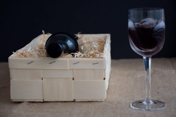 Bottle of wine in wooden box with straw - crystal wine glass with red wine